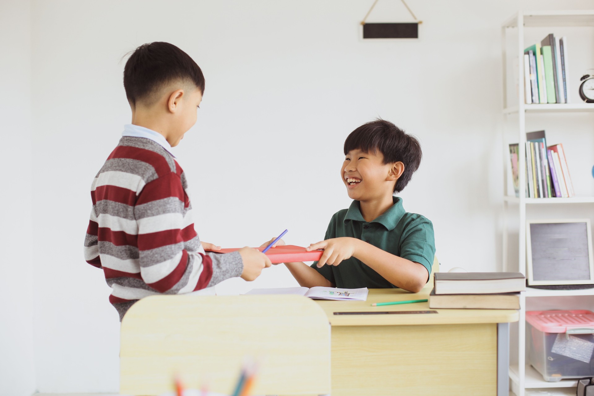 Schoolboy giving book to friend